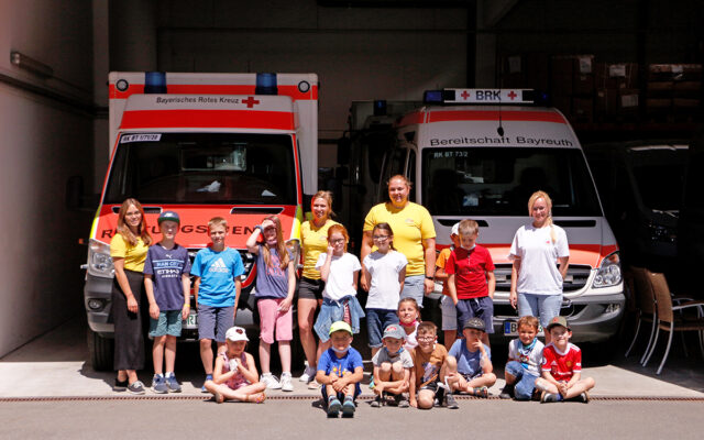 15 Mädchen und Jungen besichtigen den Fuhrpark der Einsatzfahrzeuge des BRKs in Bayreuth.