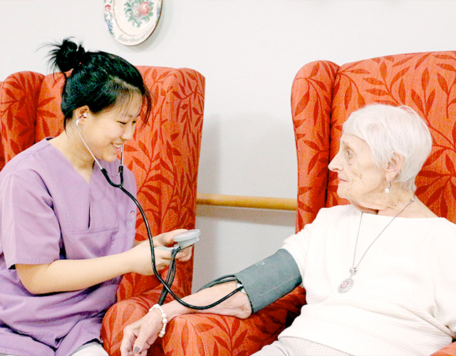 Frau misst Blutdruck an einer Seniorin