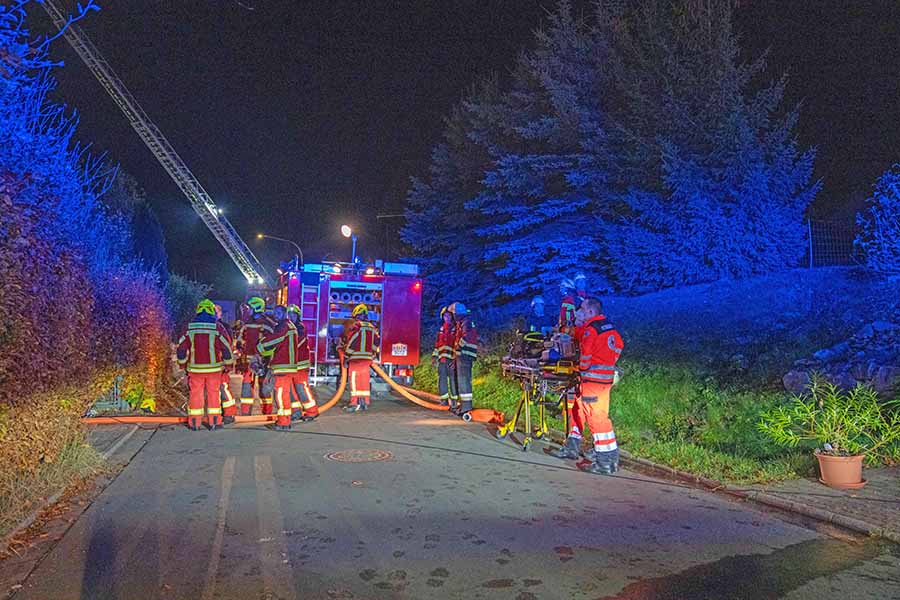 Hlfskrä#fte am Einsatzort , vor Einsatzfahrzeug der Feuerwehr mit Drehleiter.