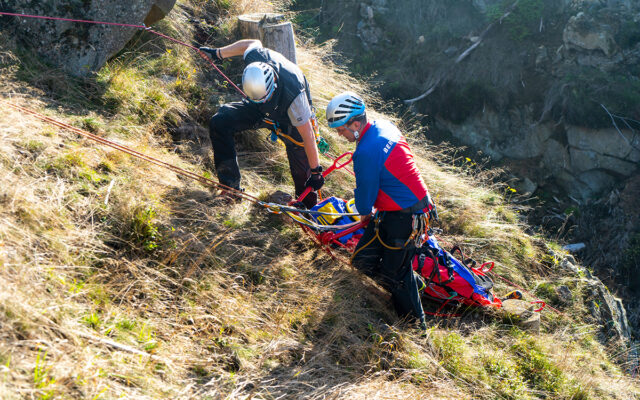 Bergung eines (fiktiv) Verletzten durch zwei Bergwachtmänner mit der Gebirgstrage am Steilhang