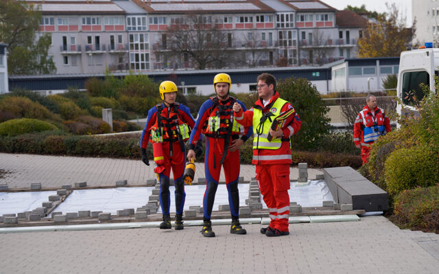 Wasserretter der Wasserwacht werden vom Einsatzleiter Wasserretter in die Lage am Einsatzort eingewiesen.