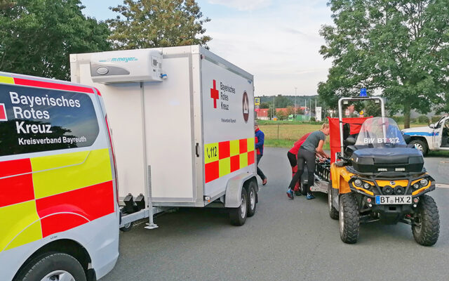 Einsatzfahrzeug der ehrenamtlichen Sanitäter:innen des BRKs mit Anhänger und Quad der Bergwacht an der Rettungswache Süd.
