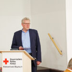 Thomas Ebersberger, Oberbürgermeister der Stadt Bayreuth und Vorsitzender des Aufsichtsrates der Klinikum Bayreuth GmbH, dankt den ehrenamtlichen Mitgliedern für ihr großartiges Engagement für das Bayreuther Klinikum. Auf dem Rednerpult die Aufschrift: Bayerisches Rotes Kreuz Kreisverband Bayreuth