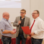 Markus Ruckdeschel (KGF, mitte) und Alexander Pscherer (Personalratsvorsitzender, rechts) überreichen die Ehrungsurkunde an Simon Schenkl (links).