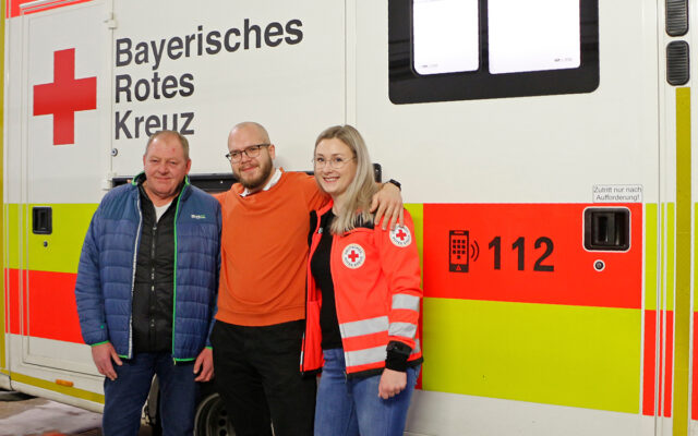 Peter Maj mit Notfallsanitäterin Lisa Prechtl und BRK-Rettungsdienstleiter Bayreuth Dietmar Kasel vor einem Rettungswagen.