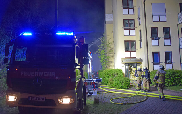 Einsatzfahrzeug und Feuerwehrleute am Brandort.