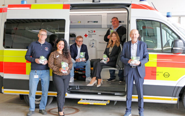 AOK Bayreuth-Kulmbach übergibt Jolinchen an BRK-Kreisverband Bayreuth. Im Bild (v.l.n.r.): Roland Wittich (Beauftragter Betriebliches Gesundheitsmanagement - BRK-Kreisverband Bayreuth), Nazmiye Önal (Direktionsassistent AOK Bayreuth-Kulmbach), Markus Ruckdeschel (BRK-Kreisgeschäftsführer Bayreuth), Jochen Pausch (Wachleiter BRK-Rettungsdienst Rettungswache Bad Berneck, hinten), Melanie Heinlein-Lodes (AOK-Direktorin Bayreuth-Kulmbach, vorn) und Frank Becher (Beratung Geschäftspartner AOK Bayreuth-Kulmbach) vor einem Krankenwagen des BRK-Kreisverbandes Bayreuth.