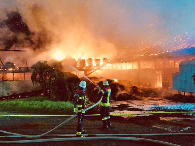 Feuerwehreinsatzkräfte wenige Minuten nach Alar- mierung bei der Brandbekämpfung von einer anderen Seite des Pferdestalls