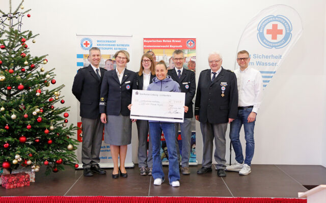 Anne Haug bei der Übergabe der gesammelten Spendengelder der sailfish night of the year in Höhe von 8.750 Euro an die Wasserwacht Ortsgruppe Bayreuth. Im Bild (v.l.n.r.): Arne Peplau (2. stv. Vorsitzender Wasserwacht Ortgruppe Bayreuth), Karil Diehl (Vorsitzende Wasserwacht Ortsgruppe Bayreuth), Sophia Lugert (Jugendleiterin der Wasserwacht Ortsgruppe Bayreuth), Anne Haug, Ulrich Brenner (1. stv. Vorsitzender der Wasserwacht Ortsgruppe Bayreuth), Hans Joachim Seibel (Vorsitzender der Kreiswasserwacht Bayreuth) und Markus Ruckdeschel (BRK-Kreisgeschäftsführer Bayreuth) im weihnachtlich geschmückten Festsaal des BRK-Kreisverbandes Bayreuth.