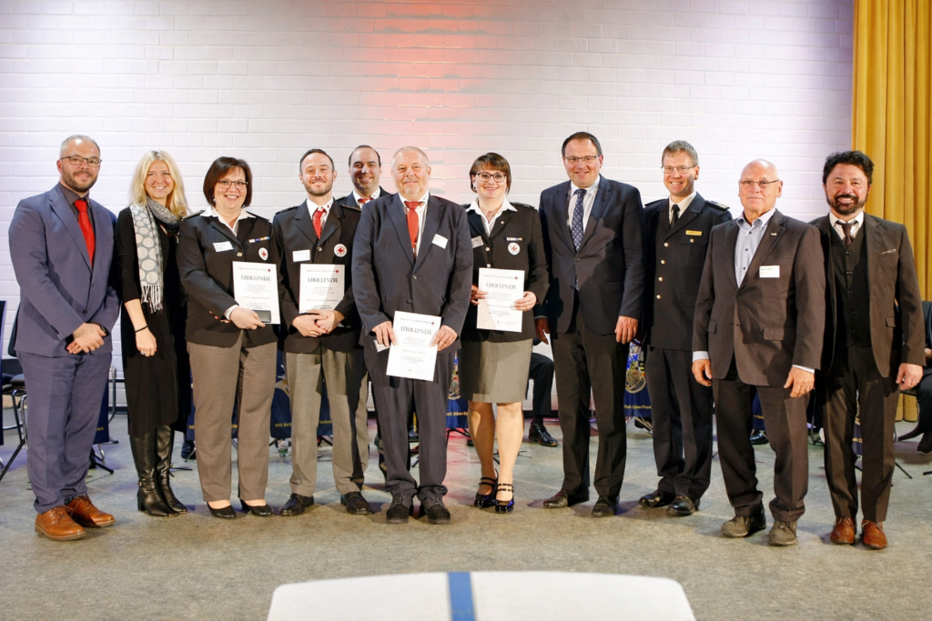Politik und Blaulichtwesen würdigen ehrenamtliches besonders Engagement in einem wichtigen Bereich. (Gruppenfoto) Im Bild (v.l.n.r.): Andreas Hanna-Krahl (BRK-Vizepräsident, MdL), Silke Launert (Parlamentarische Staatssekretärin bei der Bundesministerin für Forschung, Technologie und Raumfahrt, MdB), Silvia Pöhlmann (PSNV-Team Bayreuth/Kulmbach), Dominik Hohnerlein (PSNV-Team Bayreuth/Kulmbach), Mischa Nietfeld (stv. Kreisbereitschaftsleiter BRK-Kreisverband Bayreuth), Heiko Pöhnl (Fachdienstleiter PSNV-Team Bayreuth/Kulmbach), Lena Engelmann (PSNV-Team Bayreuth/Kulmbach), Martin Schöffel (Staatssekretär im Bayerischen Staatsministerium der Finanzen und für Heimat, MdL), Dr. Rene Mühlberger (Landeszentralstelle für PSNV Bayern), Peter Herzing (Vorsitzender BRK-Kreisverband Bayreuth) und Sven Ruhl (Bürgermeister Glashütten).