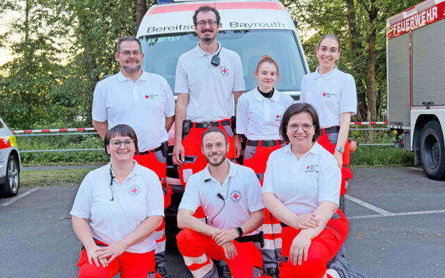 Das Team der "Volksfestwache" des BRK-Bayreuth 2026. Im Hintergrund ein Notfall-Krankenagen der Bereitschaften.