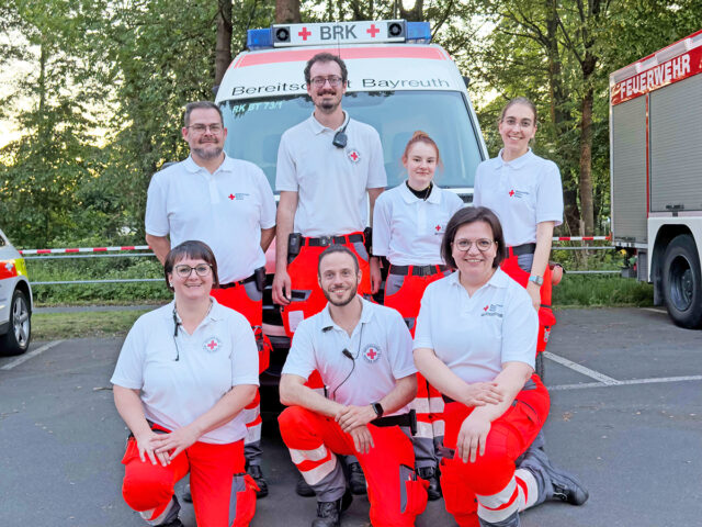 Das Team der "Volksfestwache" des BRK-Bayreuth 2026. Im Hintergrund ein Notfall-Krankenagen der Bereitschaften.